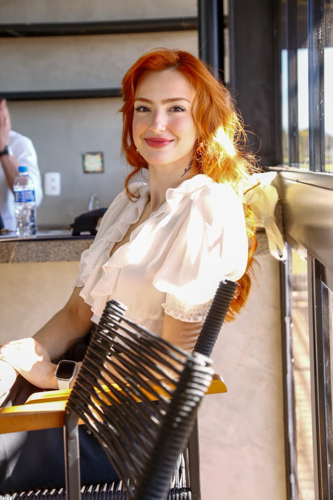 Eu sentada num balcão, de blusa branca, sorrindo com a luz do fim de tarde no cabelo.